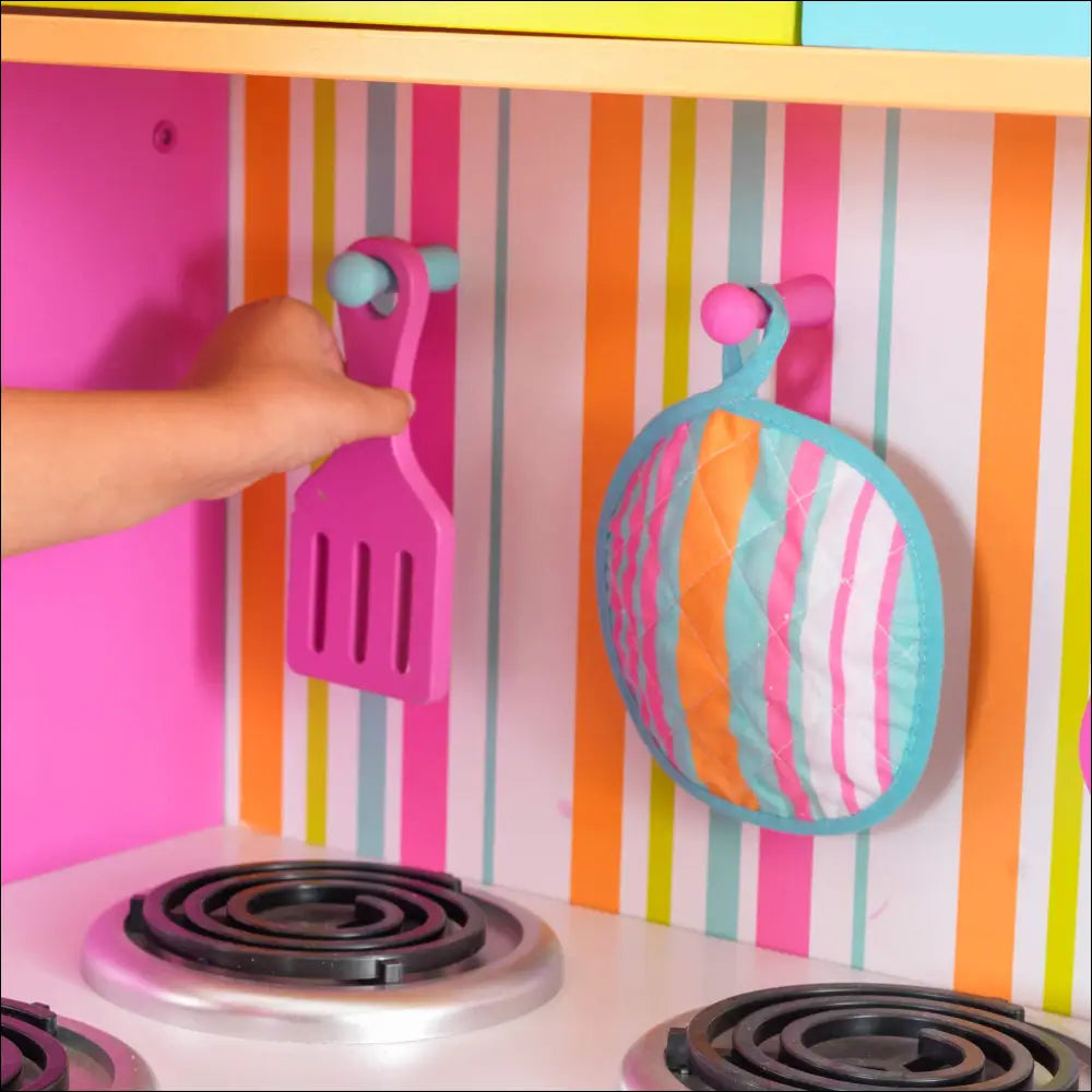 Utensilios de cocina plásticos coloridos colgando en pared rayada sobre estufa Cocinita Deluxe Big