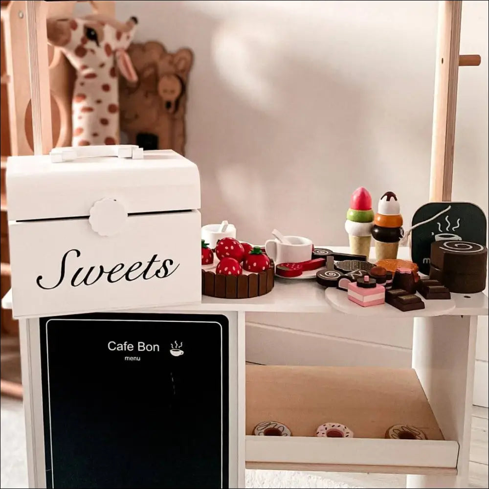 Caja de madera blanca etiquetada Sweets sobre un aparato del juego de pastelería Mamabrum
