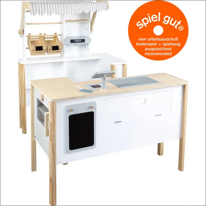 Cocina de madera con detalles blancos y etiqueta spiel gut en la Tienda-Cocina Small Foot